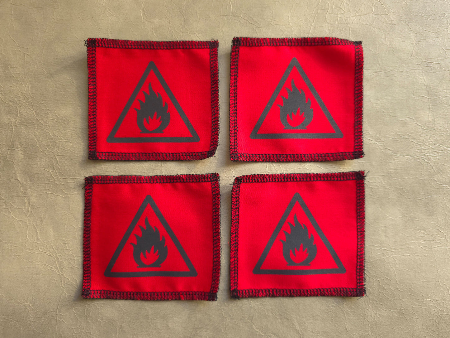 Four red patches with black fire symbol on a beige background