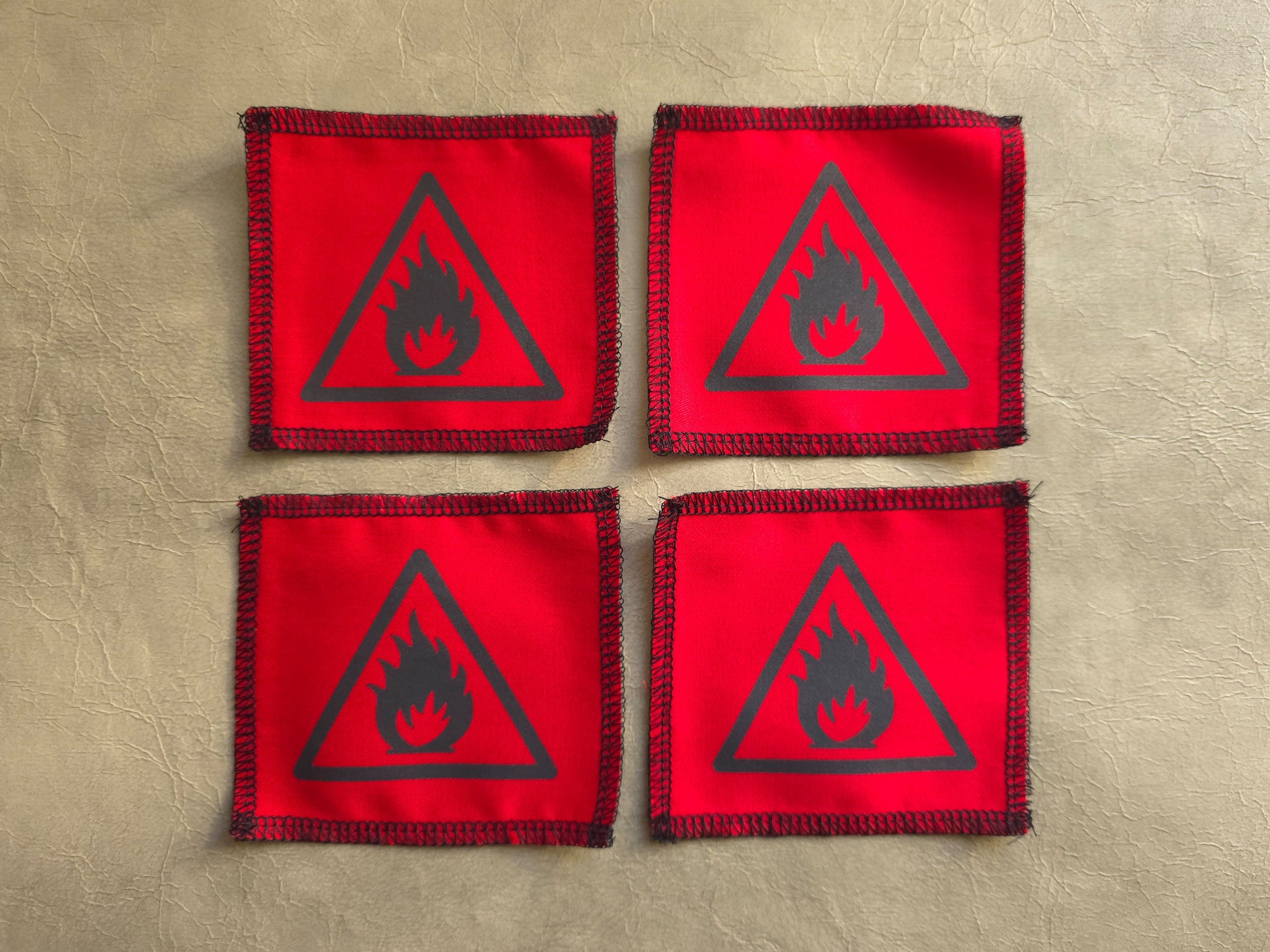 Four red patches with black fire symbol on a beige background