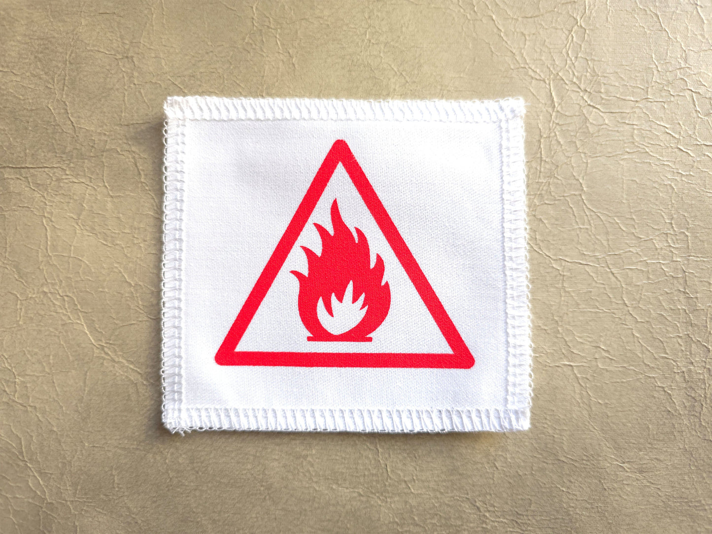 Flame warning sign patch on a beige background