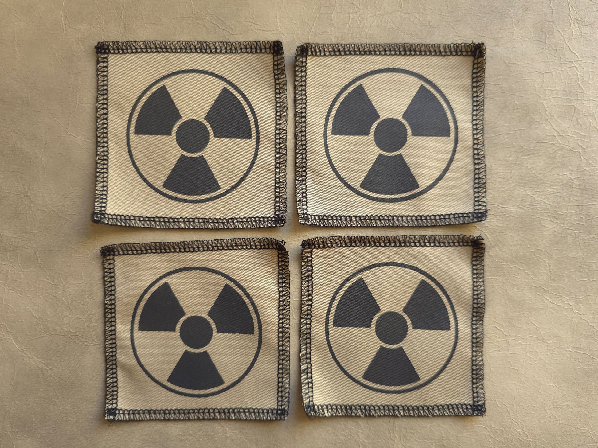 Beige handmade screen printed radioactive symbol patches arranged in a group display