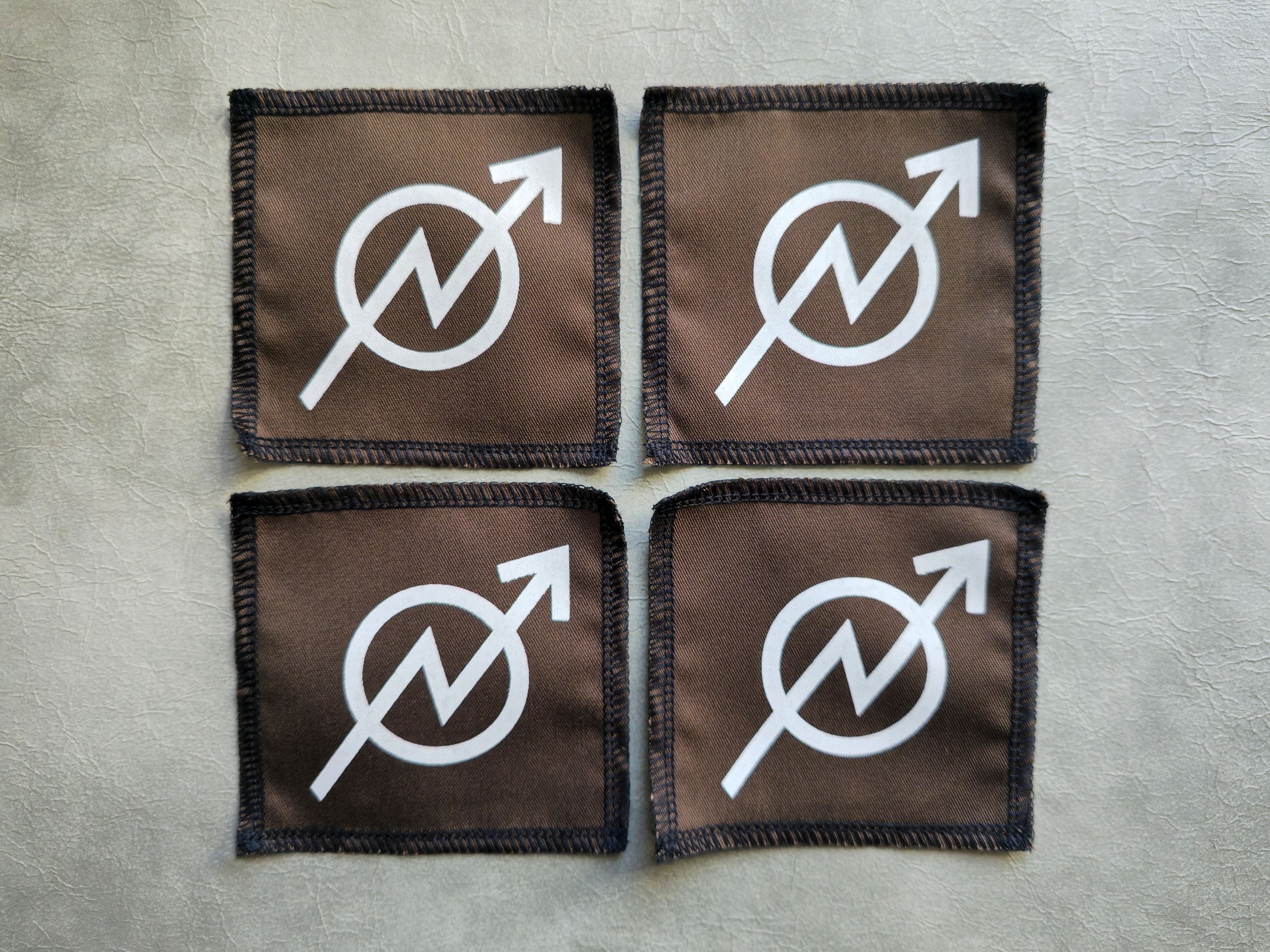 Brown handmade screen printed squat symbol patches displayed in a group layout