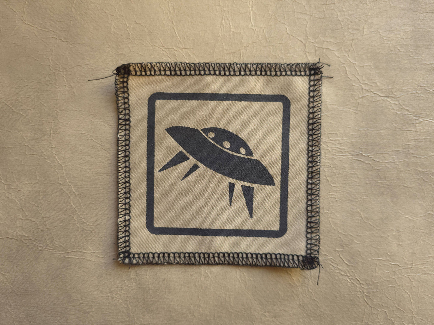 Patch with a UFO design on a beige background