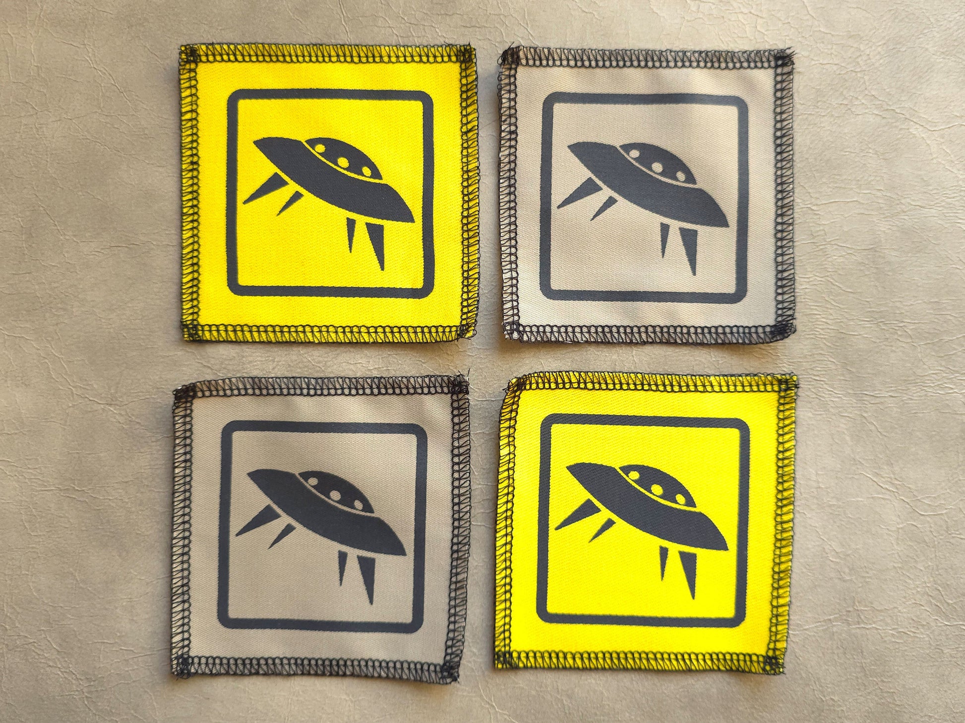 Four patches with UFO symbols on a textured surface