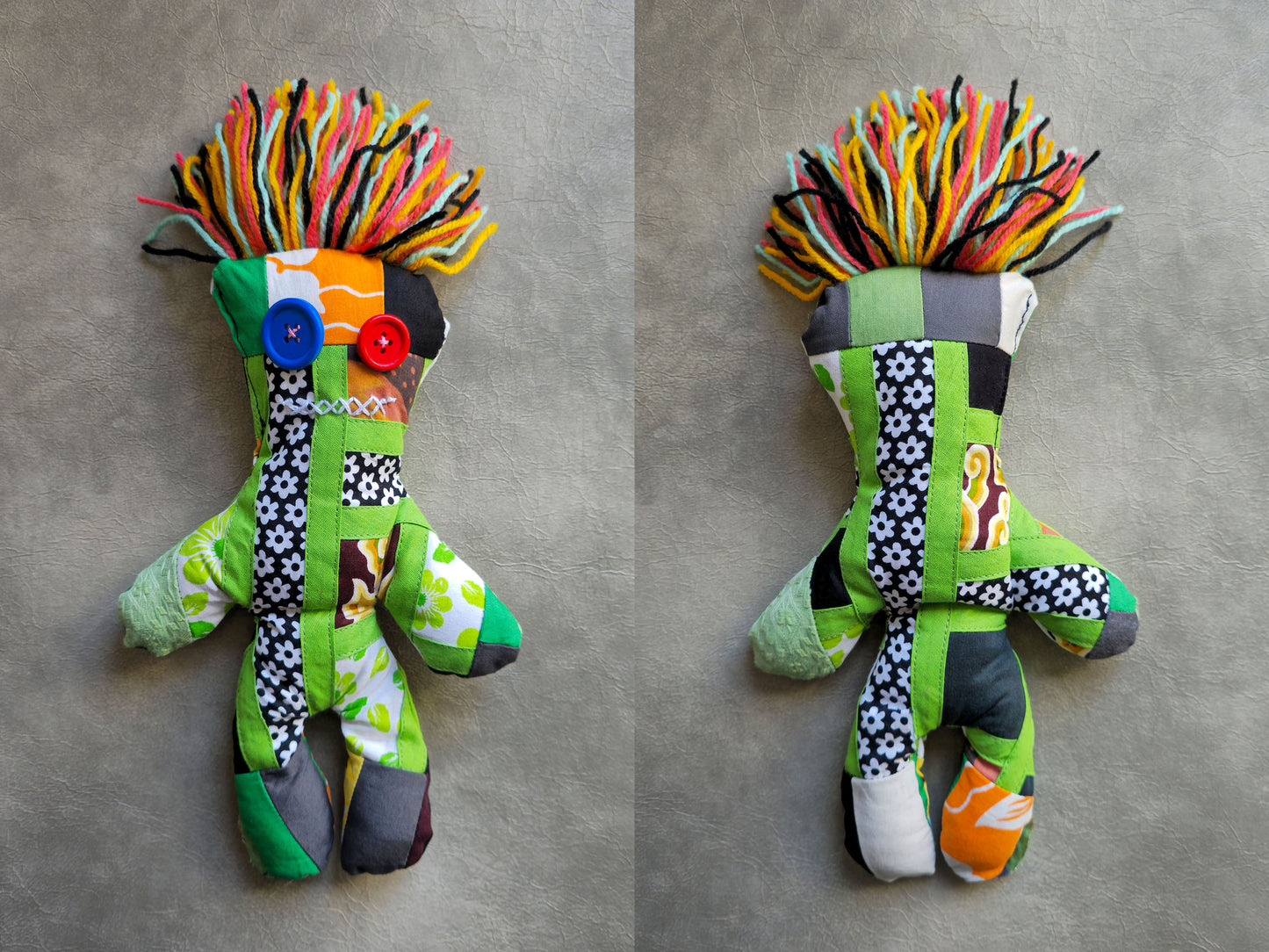 green voodoo doll stuffed toy with patterned woolen hair on a gray background