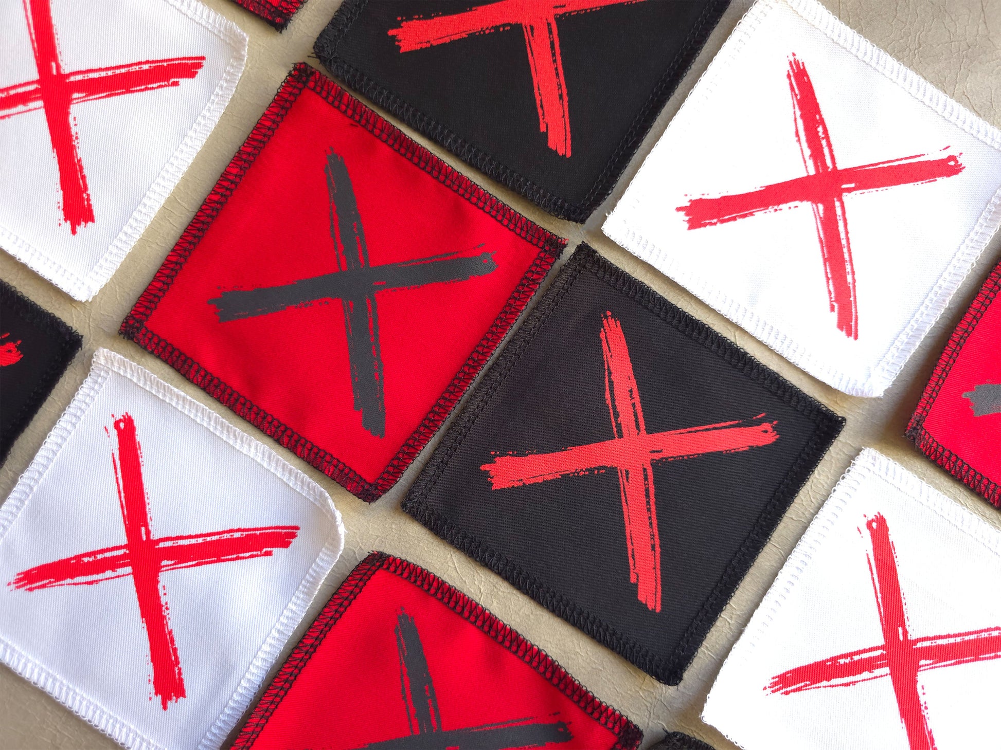 Angled view of handmade screen printed x symbol patch highlighting fabric texture and print detail