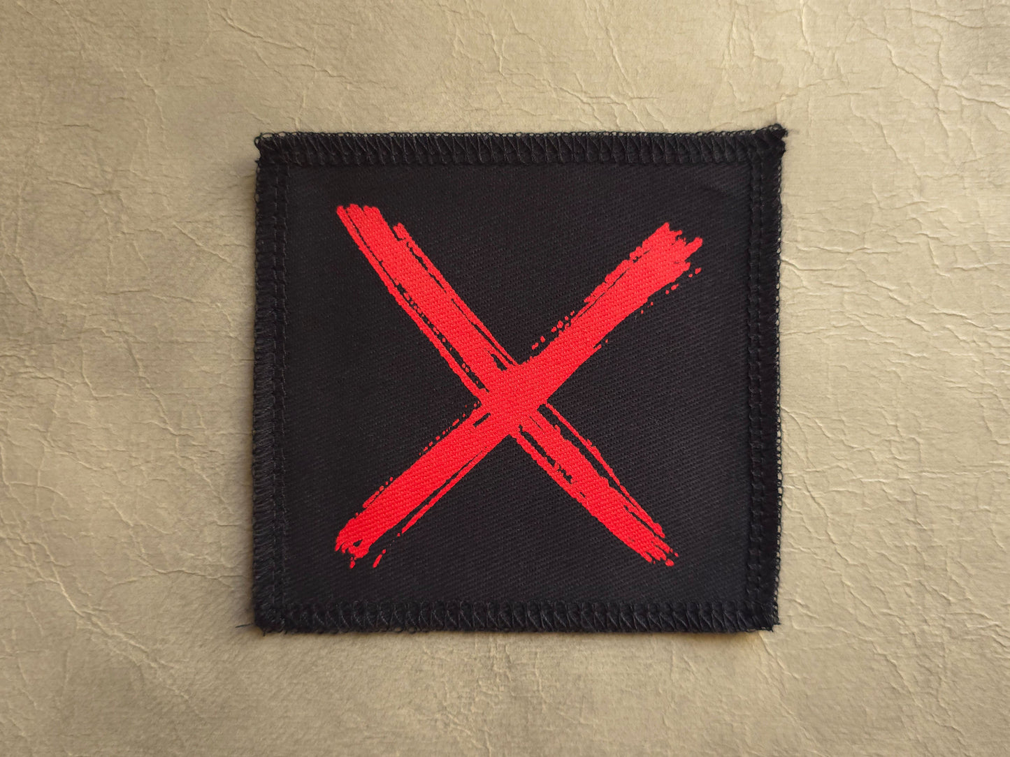 Black handmade screen printed x symbol patch with high-contrast printed graphic