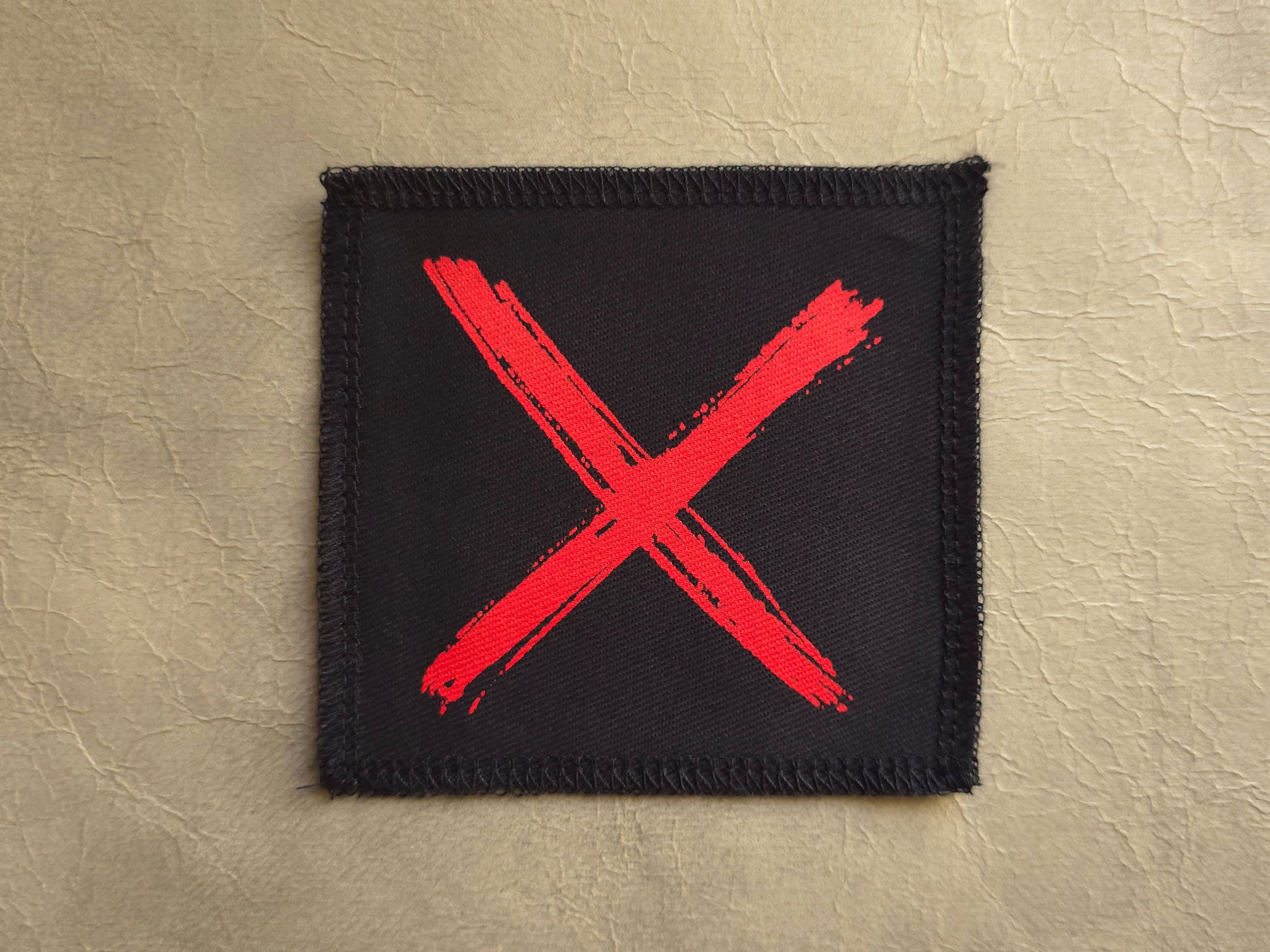 Black handmade screen printed x symbol patch with high-contrast printed graphic
