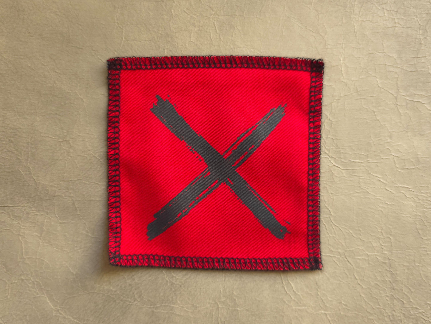 Red handmade screen printed x symbol patch featuring bold printed symbol