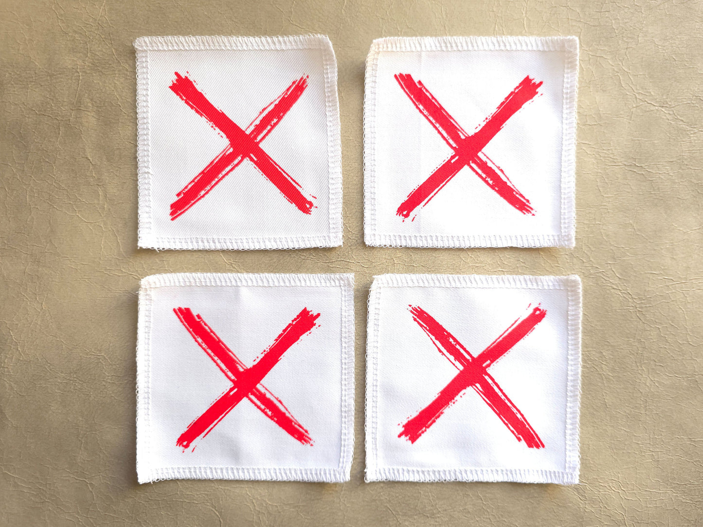 White handmade screen printed x symbol patches displayed as a set