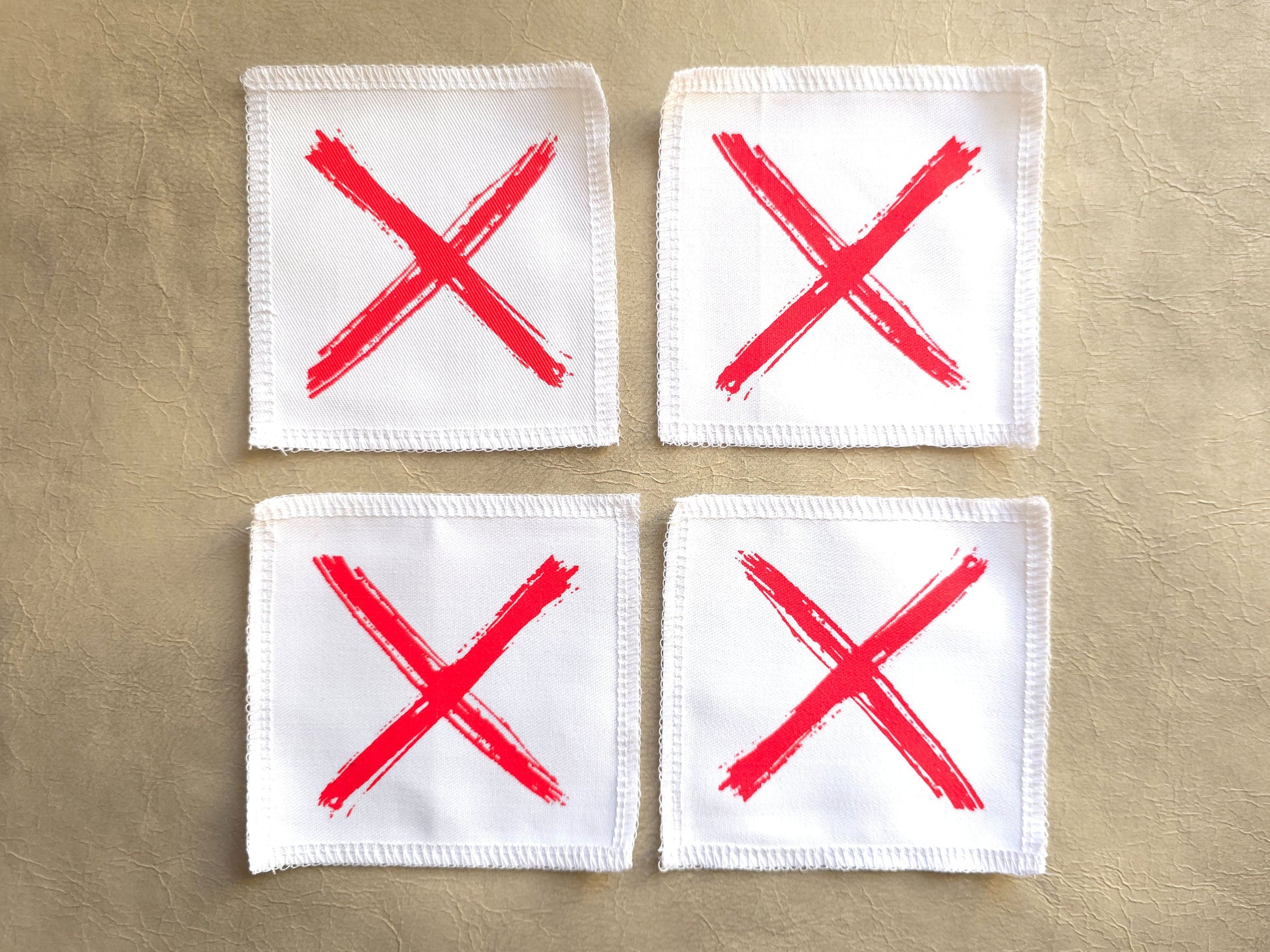 White handmade screen printed x symbol patches displayed as a set